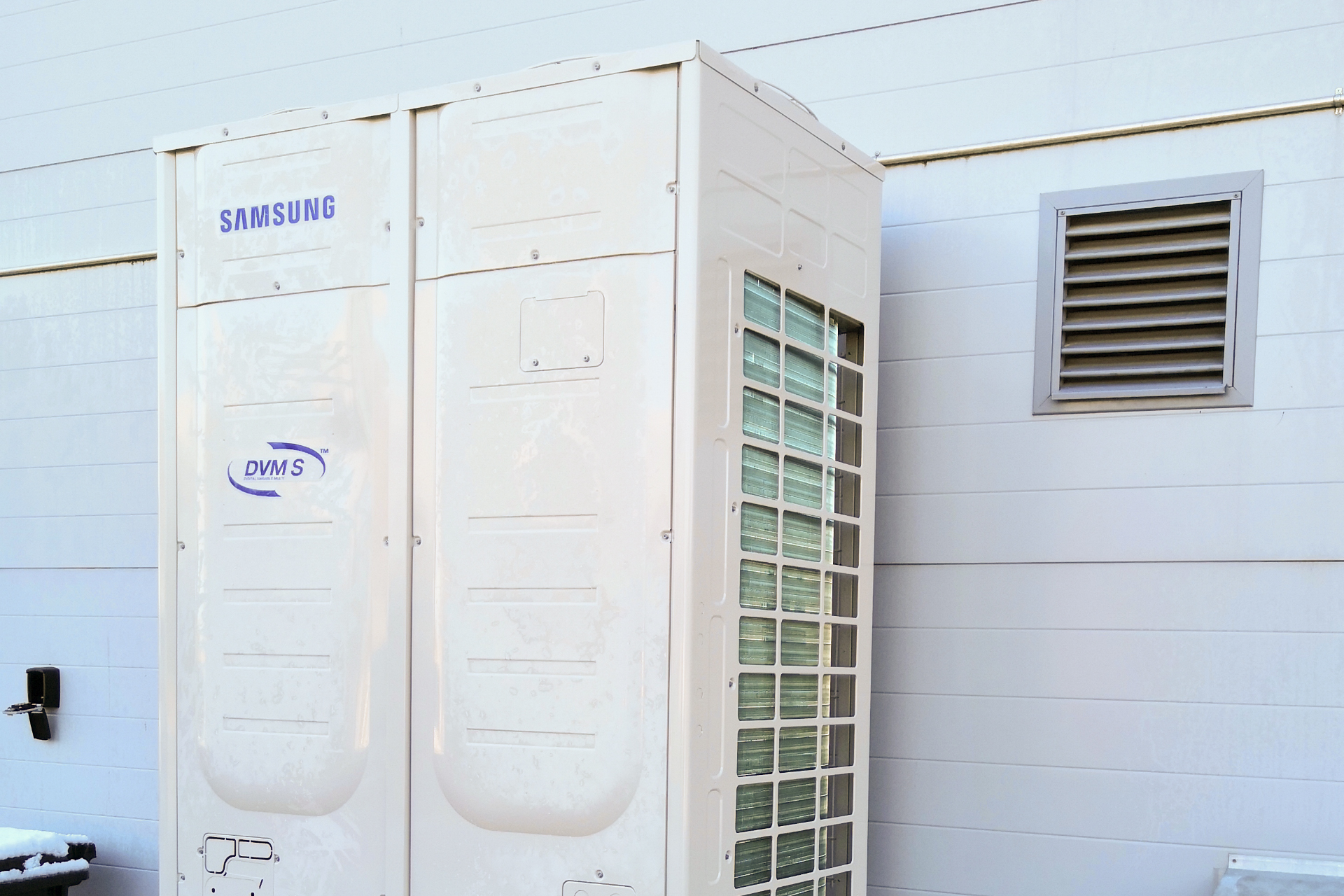 Outdoor heat pump equipment beside a production hall.