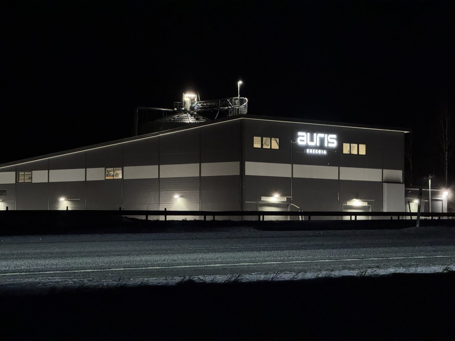 An illuminated Auris Energy building at night.